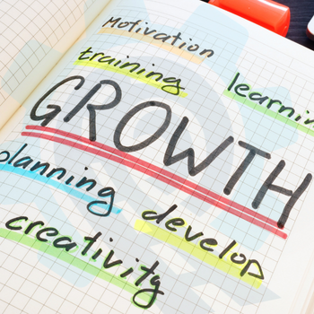 Open notebook with handwritten words: growth, development, motivation, training, planning, and creativity — representing leadership capability and strategic planning.